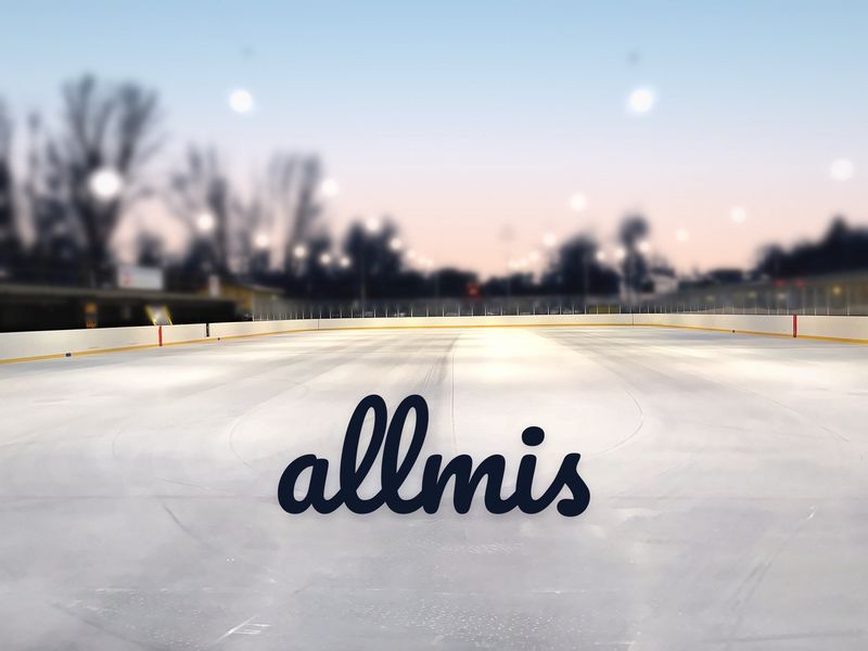En spolad isbana i skymningen med Allmis-logotypen på isen